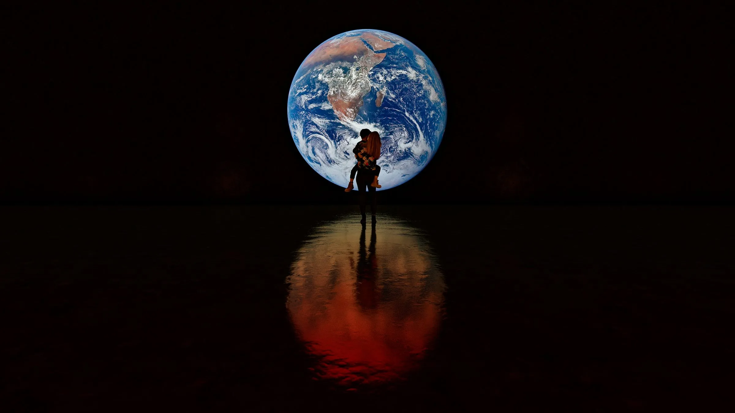Two figures silhouetted against a luminous Earth globe in an immersive exhibition
