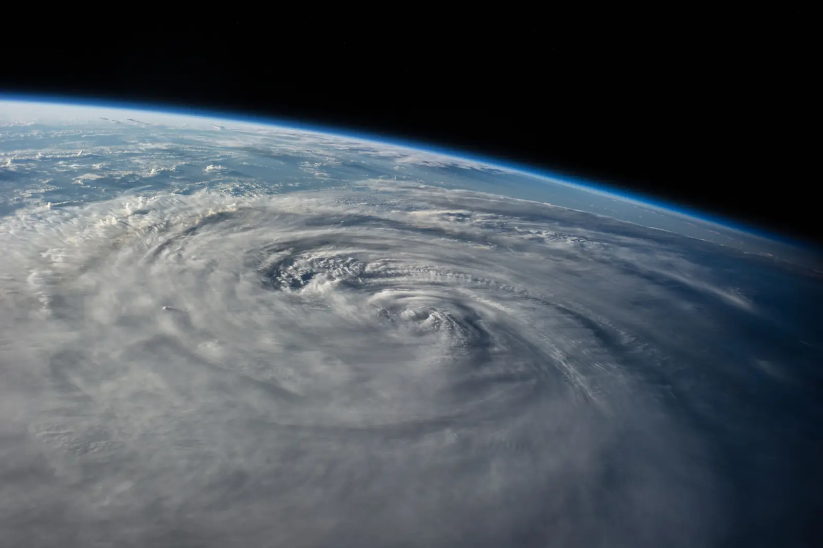 Earth's limb seen from orbit, a cyclone spiralling over the ocean